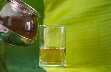 Coffee drink in a glass decorated with flowers and banana leaves.