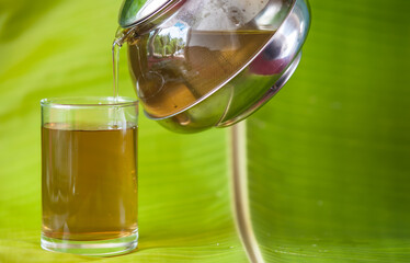 Coffee drink in a glass decorated with flowers and banana leaves.