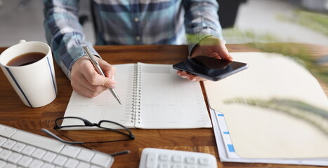 Close-up of person start day right with planner and cup of coffee, make appointment, plan. Journal,...
