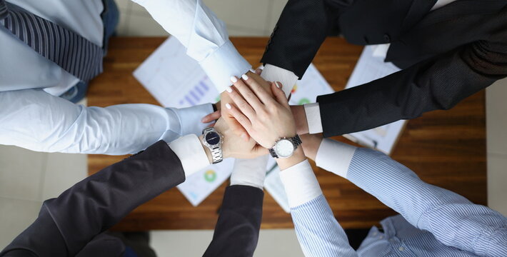 Top view of colleagues performing gesture in order to prepare for important profitable project, change future of corporation. Teamwork, business concept