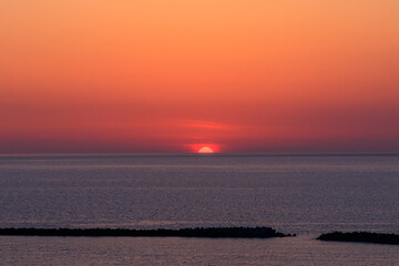 春の新潟の真っ赤な夕焼けと海に半分沈みかけている太陽