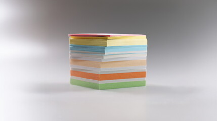Close-up of uneven stack of sticky post it note on grey surface, bunch of clean papers. Bright...