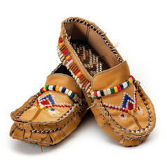 A pair of kids' moccasins in tan with a beaded design, isolated on white background