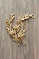 Branch with leaves and flowers is made of straw. Straw wall decoration. The products are made of straw. Decoration of straw on a wooden background