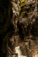 Brown textured stone walls in a dark rocky gorge tunnel in Partnachklamm