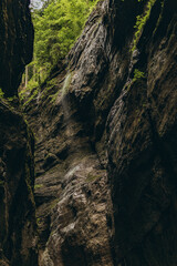 Brown textured stone walls in a dark rocky gorge tunnel in Partnachklamm