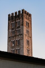 San Frediano church tower with intricate windows against a clear blue sky at sunset