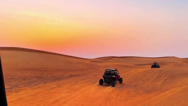 Silhouette dune buggy explores the abandoned terrain of the sweltering desert during a sunset sandstorm. High quality 4k footage