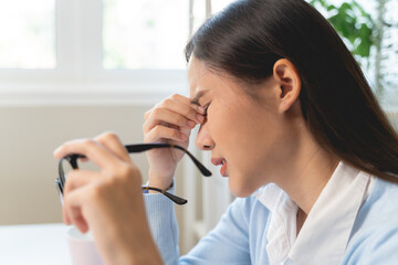 woman taking off glasses tired of computer work suffering from eye strain tension