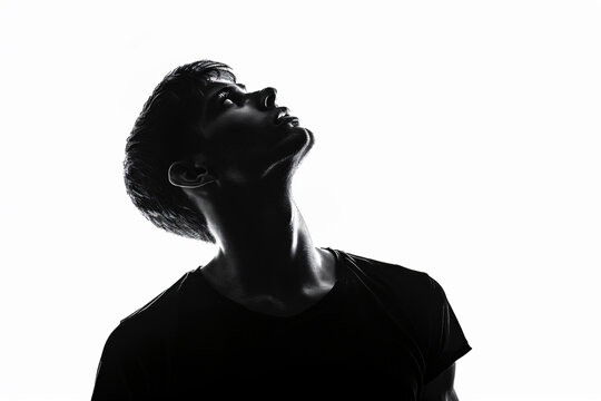 Silhouette of handsome man in black t-shirt on white background, isolated portrait of young guy with short hair and sidecut looking up, profile view, isolated


