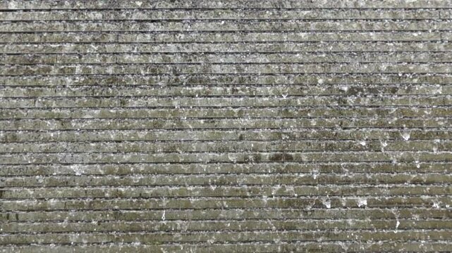 Falling water in slow motion in front of a gray stone wall 