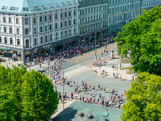 An energetic aerial shot capturing marathon runners weaving through the streets of Riga, Latvia, with buildings lining the route, showcasing the event's excitement.