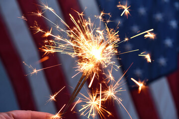 Holding sparklers in front of an American Flag to celebrate patriotic holiday - the 4th of July USA Independence Day, Memorial Day or Veterans Day