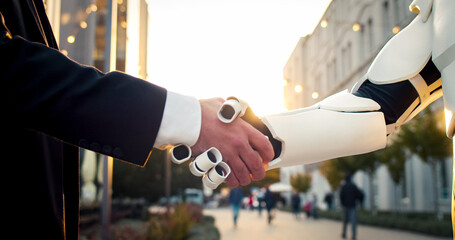 Shaking hand with artificial intelligence machine. Businessman shakes iron robot's hand. Agreement...