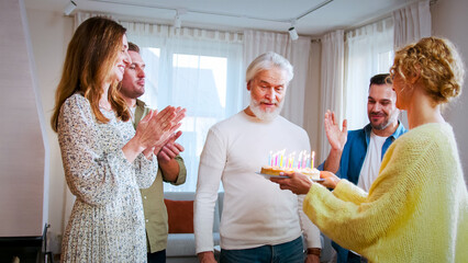 Portrait of oldest member of family prepares to blow out candles on birthday cake in front of...