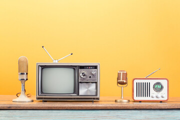 Old TV, FM radio, gold microphones front yellow background. Retro style filtered photo