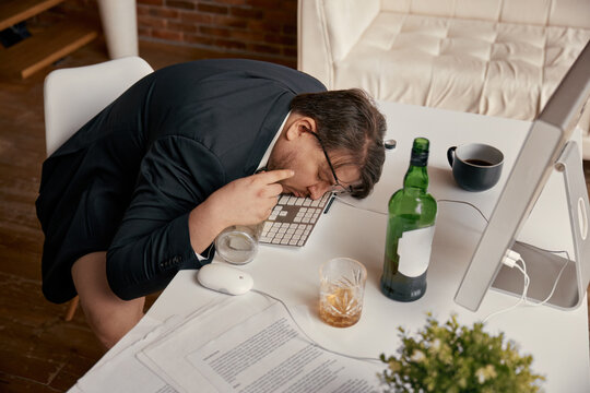 Businessman drunkard sleeping at desk in home office workplace