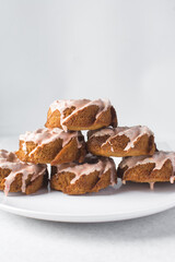 Iced mini bundt cakes stacked on a white plate, glazed vanilla and citrus bundlettes on a plate, small vanilla bundt cake with an icing glaze