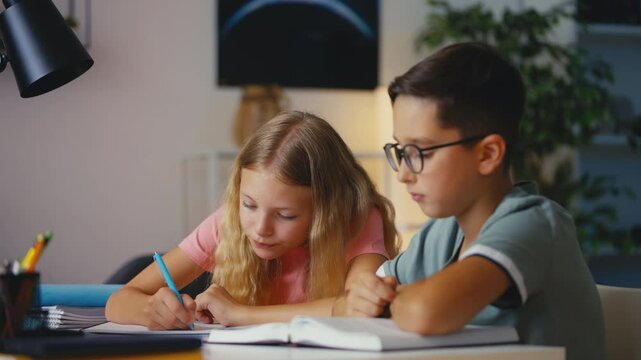 Young boy and girl doing a school project together, writing in notebooks