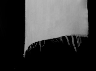 hanging teared rag spread isolated on black background , can use like a background or any texture. hole in the tissue. white fabric with torn stitch, hole and loose threads