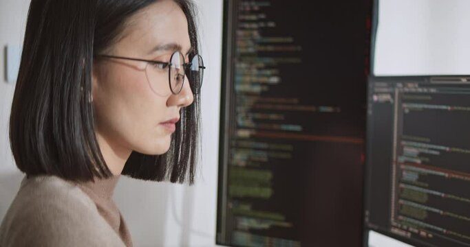 Young adult Asian male, female software developer coding program on desktop computer. Woman work from home, remote working, freelance programmer job, smart digital nomad lifestyle concept