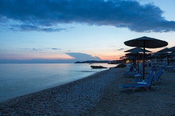 Evening hotel beach on the island of Thassos in Greece. There are umbrellas and sunbeds on the beach.