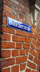 Obraz premium Blue german street sign with white letters indicating Boticherstraße on a red brick wall