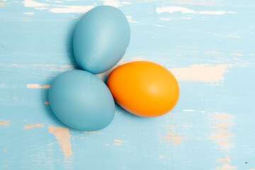 Eggs symbolizing the Easter holiday in blue and orange color on a background of aged wood