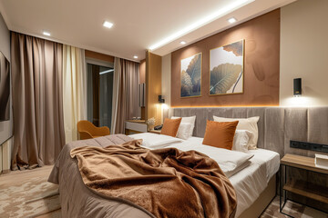 Fototapeta premium A bed with a brown comforter and pillows, and a lamp on the nightstand, generative ai image.