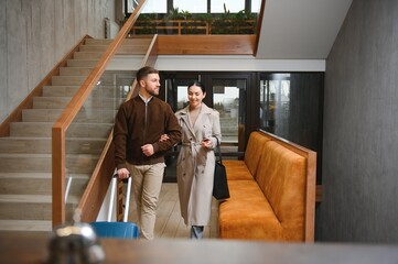 Young couple near reception desk in hotel. Young couple leaving hotel