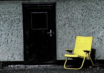 Weathered Urban Door with Yellow Wicker Chair Against Textured Wall, Rustic Minimalist Aesthetic