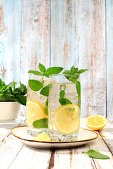 Medicinal herbal tea or peppermint infusion with lemon and ice, concept of detox diet and alternative traditional medicine, collection of useful herbs for treatment according.