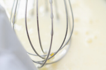 A whisk is sitting in the dough in a loaf tin with a sheet of parchment paper