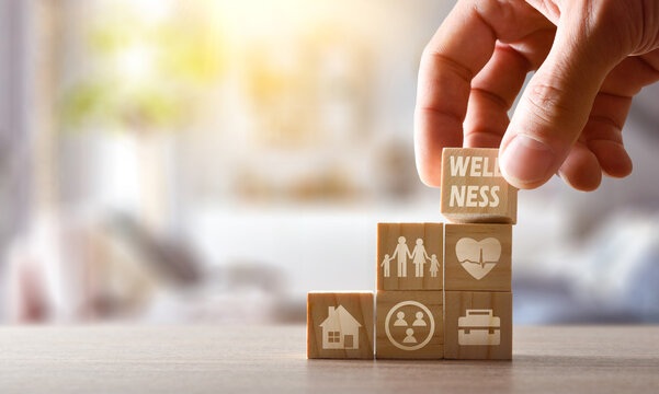 Hand stacking cubes on table at home with wellness symbols