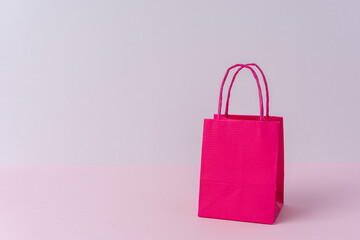 Colorful paper shopping bag on bright background. Creative minimal shopping concept.