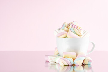 Marshmallows colorful chewy candy in a cup on pink background. Sweet holiday food concept.