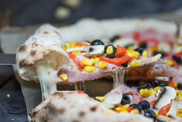 Delicious pizza slices with pepperoni, olives, ham, mushrooms, red pepper and corn, americano style