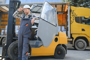 Portrait of heavy industry forklift driver giving thumbs up and smiling