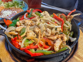 Chicken fajitas with peppers and onions in an iron skillet