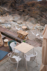 Beachside Cafe Chairs and Tables Overlooking Rocky Shoreline: Tranquil Seaside Retreat