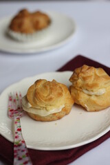 Two kue sus or profiteroles, or cream puff or choux on white plate. Selective focus