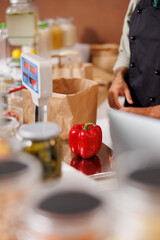 Close-up of a freshly harvested red bell pepper placed on electronic scale for weighing and checking of price. Detailed image of vendor measuring the weight of locally grown products for clients.