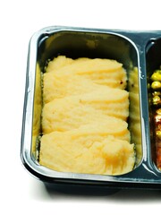 High quality mashed potatoes portion in a black plastic tray on white background. Part of a take away dinner or lunch. Office food.