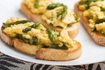 Toast or slice of toast with scrambled egg and green asparagus.