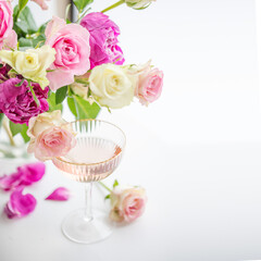 A glass of rose champagne and a bouquet of pink roses