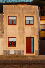 Traditional Portuguese house facade with red windows and weathered orange walls in Porto