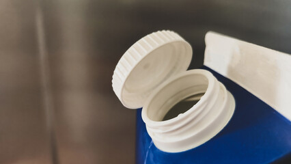 Open Blue Plastic Bottle Close-up. A detailed view of an open blue plastic bottle with a white cap,...