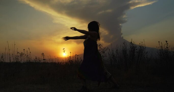 Mexican girl in full shot dancing free style at sunset with the popocatepetl in the background