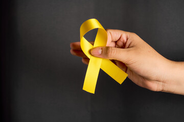 Female hand holds yellow ribbon, for suicide prevention day, concept hope.