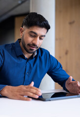 Using tablet, businessman working at desk in modern office setting